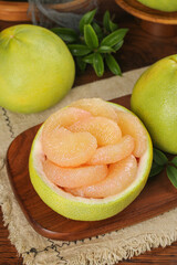 Fresh Pomelo Citrus Fruit Cut Open Showing Pink Segments on Wooden Board with Whole Fruits