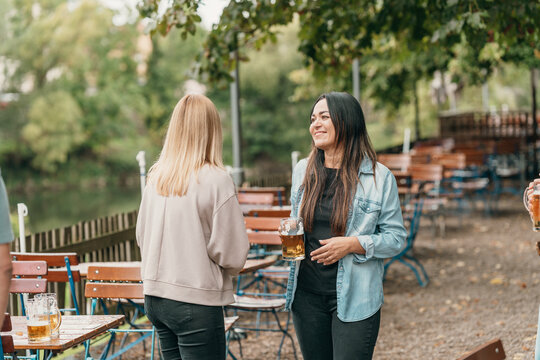 A cheerful group of friends celebrates in a Bavarian beer garden during summer enjoying cold beer together with laughter joy culture and festive mood