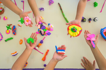 Children showing colorful playdough creations in classroom, kids holding handmade clay art, creative learning activity, preschool education, art and craft skills at school.