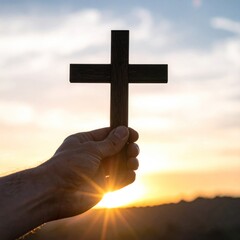 Upward view of a hand holding a dark wooden cross against a bright sunset sky, representing faith and hope in a serene setting