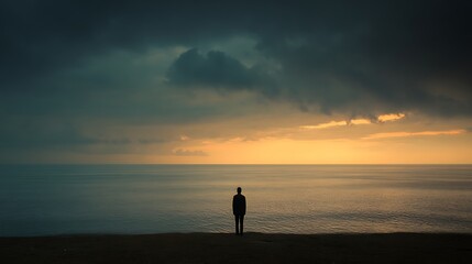 The shadow of a lone person standing facing the vast ocean conveys a sense of tranquility and emptiness.