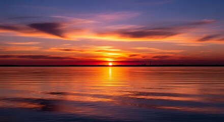 A stunning sunset paints the sky with vibrant hues over a tranquil body of water, reflecting the fiery colors beautifully.