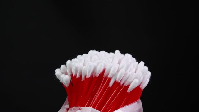 Cotton swabs in bag rotating, cotton buds on black background side view. Personal hygiene and cosmetic items. Ear cleaning q-tips