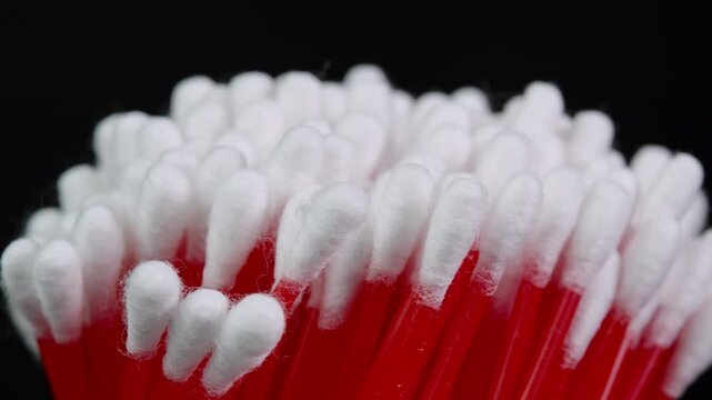 Cotton swabs in bag rotating, cotton buds on black background side view cloe up. Personal hygiene and cosmetic items. Ear cleaning q-tips