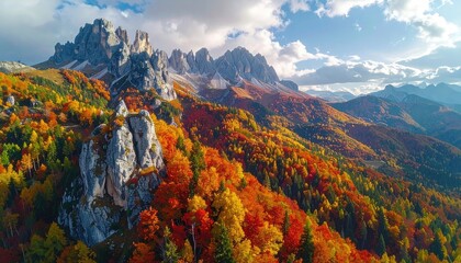Aerial View of Autumn Mountain Range with Snow Capped Peaks and Colorful Trees Under Cloudy Sky