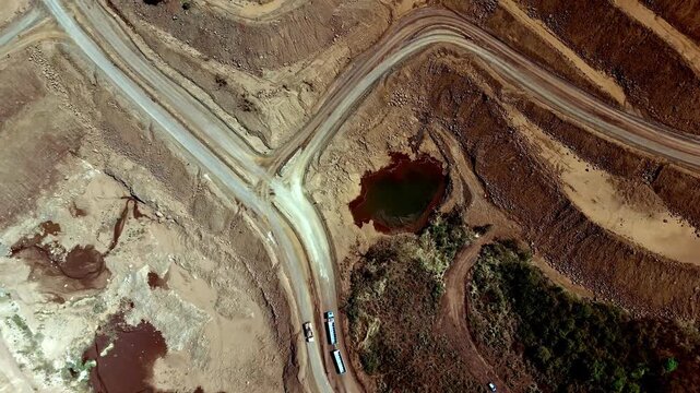 Aerial birds-eye view of nickel mining operations with trucks moving along winding roads, quarry pits, and extraction areas in an industrial mining landscape