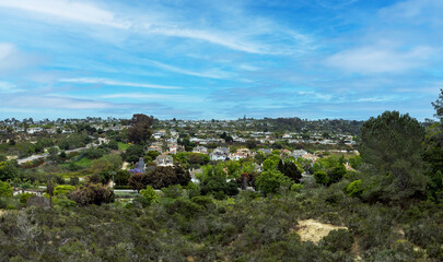 Scenic panoramic view of Encinitas residential neighborhood with houses, trees, and rolling hills under a bright blue sky and light clouds on a clear day