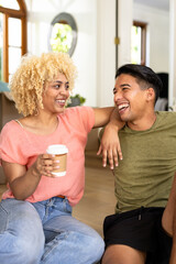 Young couple laughing together at home, enjoying coffee and conversation
