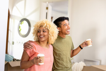Young couple enjoying coffee at home, smiling and embracing in cozy living room