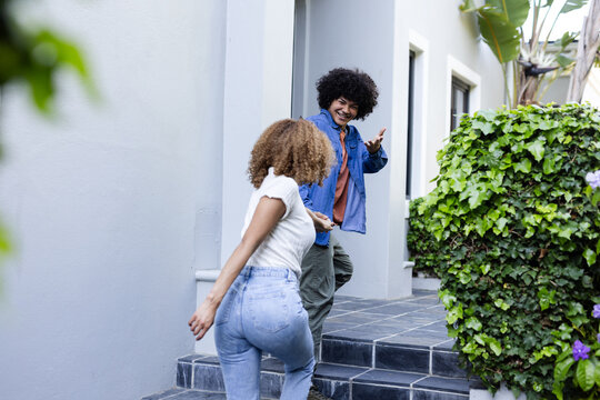 Young friends laughing and greeting each other outside modern home - Powered by Adobe
