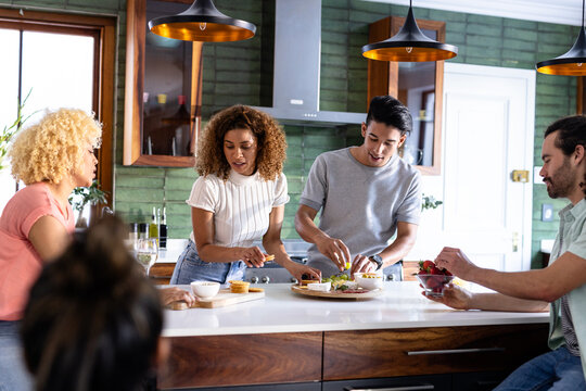 Young friends preparing meal together in modern kitchen, enjoying cooking experience