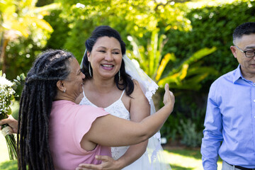 Celebrating joyful senior wedding moment, bride in white dress hugging friend outdoors