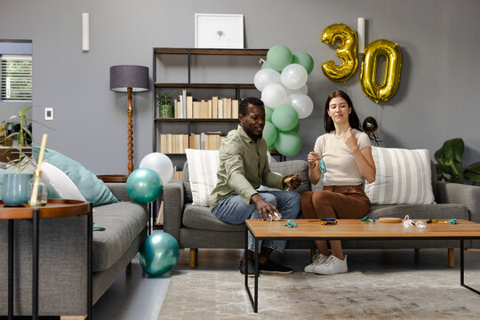 Decorating living room with balloons for 30th birthday celebration, feeling joyful