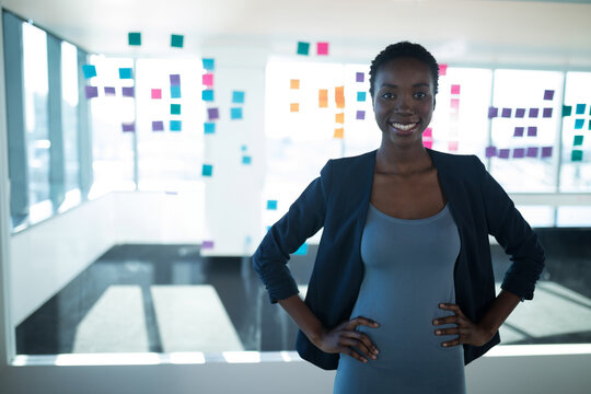 Confident businesswoman standing in modern office with colorful sticky notes