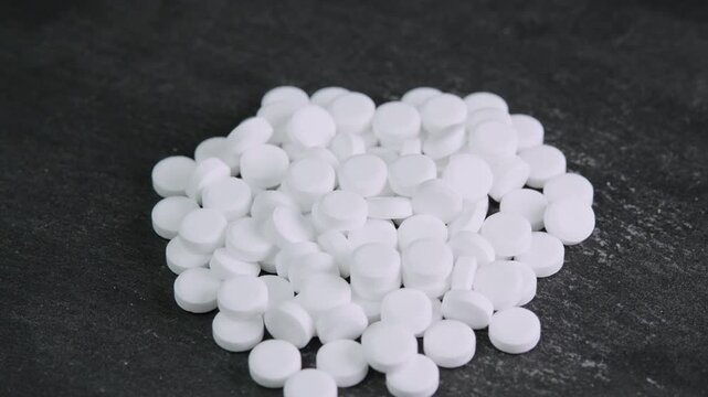 Sugar substitute tablets rotating on black surface. Artificial sweetener pills zero calories