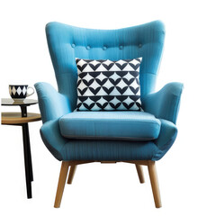 A stylish blue armchair with a patterned pillow beside a small table and a decorative mug.