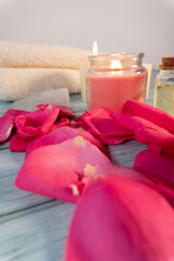 Close-up of rose petals on a spa table with candles and towels in the background