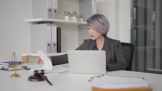 Asian adult legal professional studies case documents laptop office environment law firm expert advisor reviewing client files justice concept