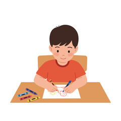 Boy at a desk is drawing on a piece of paper with crayons, smiling warmly