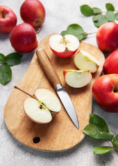 Fresh red apples and slices with knife on wooden cutting board