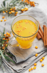 Sea buckthorn tea with berries and cinnamon sticks on grey napkins