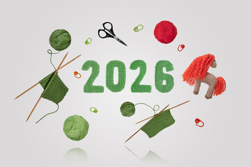 Knitting winter and Christmas decorations and clothing. Scissors, balls of yarn, a horse symbol of the Chinese New Year, and knitted numbers 2026 on a gray background float in the air.