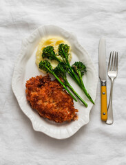 Chicken schnitzel, mashed potatoes, grilled broccoli on a light background, top view