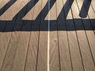 Wooden deck with painted lines casting shadows, showing texture and detail.