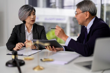 Asian adult lawyers discuss legal documents during serious consultation meeting in modern office environment