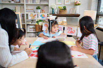 A group of girls with Down syndrome are practicing drawing in a special education classroom