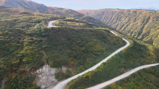 Autumn dirt road through Viluchinsky Pass, Kamchatka. Slopes with colorful vegetation. 825 m pass southwest of Petropavlovsk-Kamchatsky in South Kamchatka Nature Park.