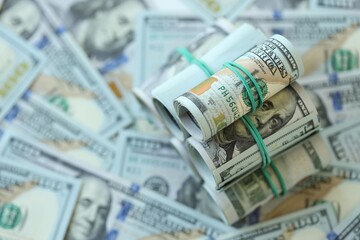 Many rolls of one hundred dollar bills lies on big amount of american currency banknotes