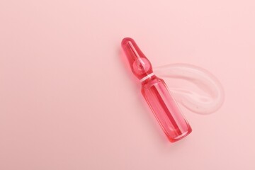 Glass ampoule with cosmetic product on pink background, top view. Space for text