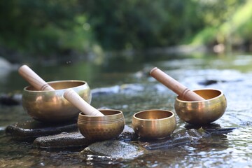 Tibetan singing bowls with mallets on stones in river