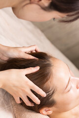 Naklejka premium 若いアジア人のエステティシャンはヘッドマッサージしている。