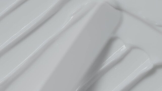Close up of spatula smear white skin care cream texture. Skincare stroke background. Cosmetic product swatch