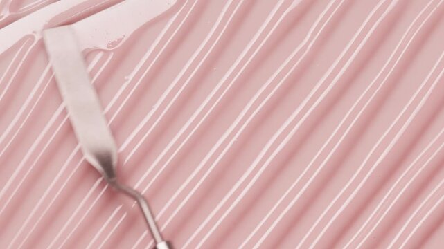 Close up of spatula smear pink lip gloss texture, satisfying lipgloss texture stroke. Cosmetic product swatch background	
