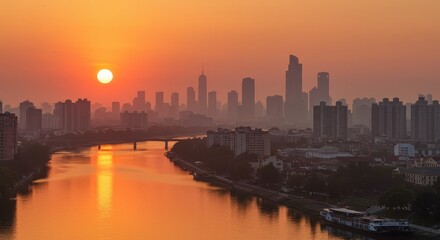 A vibrant cityscape awash in the warm hues of sunrise over a calm river, showcasing tall buildings silhouetted against a hazy sky.