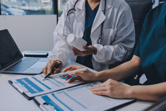 Medical team meeting analyzing blood test results in hospital laboratory. Doctors and scientists in lab coats are having a discussion about blood test result, holding test tubes and taking notes.