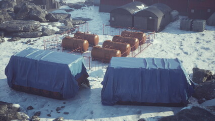 In a stark and frozen environment, a cluster of futuristic research facilities is positioned on snow covered terrain.