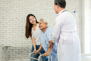 Smiling senior patient using a walker receives support from a doctor and family caregiver in a bright clinic, symbolizing rehabilitation, mobility assistance, and compassionate healthcare.