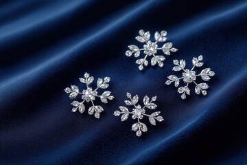 Elegant silver snowflake brooches arranged artistically on dark blue satin fabric, highlighting their intricate designs and sparkling details.