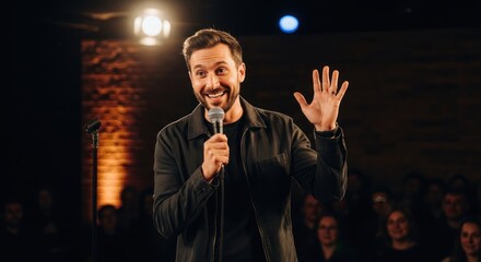 A man in a black jacket standing on a stage, holding a microphone and waving his hand.