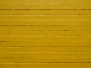 Yellow painted brick wall with regular joints and textured surface. Close-up. Copyspace.
