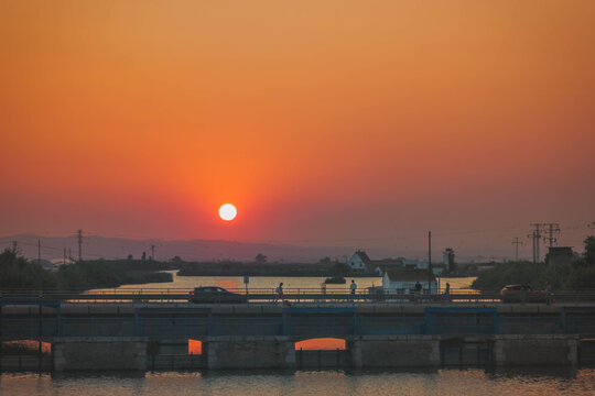 Beautiful sunset with a yellow sky over the Albufera natural park water and typical Valencian huts in Perello Bridge