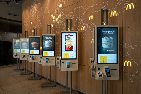 Chicago, IL, USA - Aug 27, 2025: Self-service kiosks and a McDonald's world locations map at the McDonald's Global Menu Restaurant on McDonald's Corporation's headquarters campus in Chicago, Illinois.