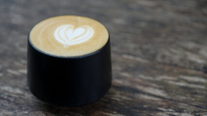 Cup of hot cappuccino with latte art on wooden table. Image in top view.