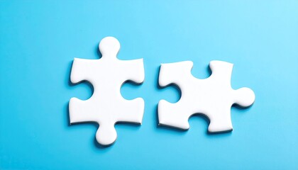 Obraz premium Two white puzzle pieces, nearly joined, on a light blue surface