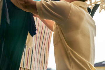 Fototapeta premium 洗濯物を取り入れる男性の連続写真。家事をする男性。