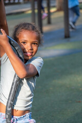 African American girl joyfully playing on playground equipment, showcasing her playful spirit and innocence during a sunny summer day with vibrant outdoor surroundings and sense of childhood happiness